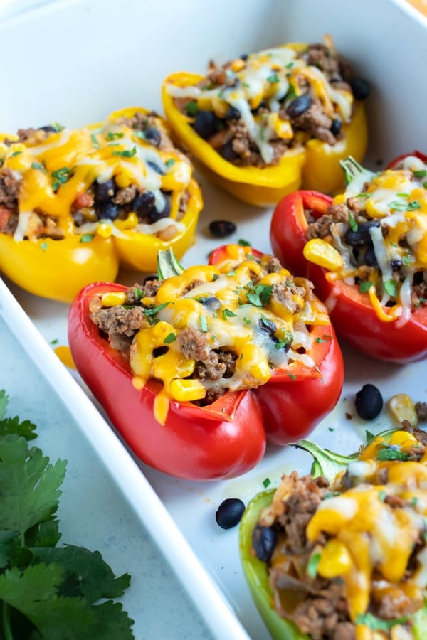 Mexican stuffed bell peppers are served from a white dish.