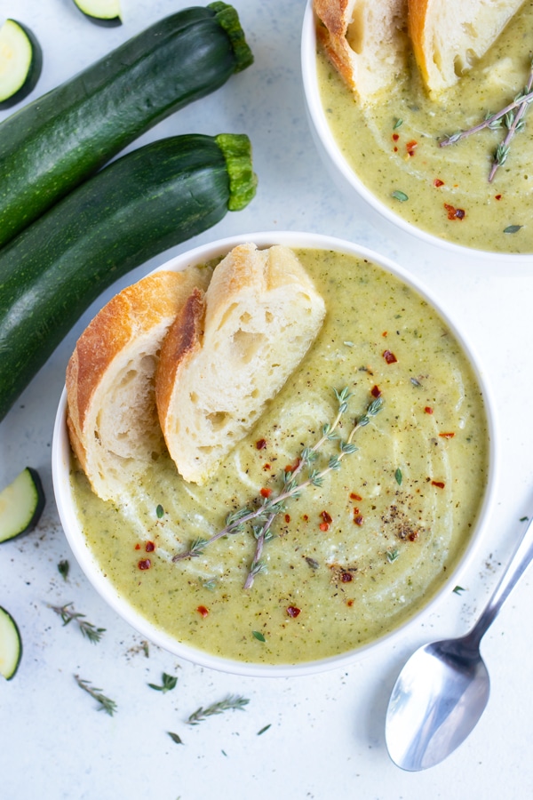Bowls of creamy zucchini soup are set on the counter.