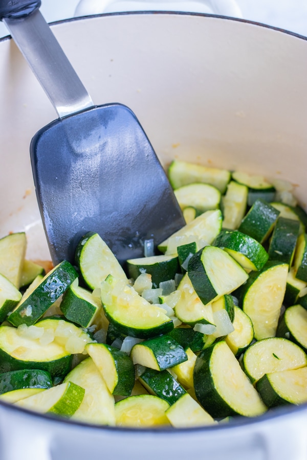 Zucchini slices are sautéed on the stove.