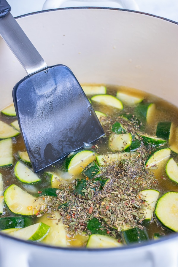 The broth is added to the zucchini on the stove.