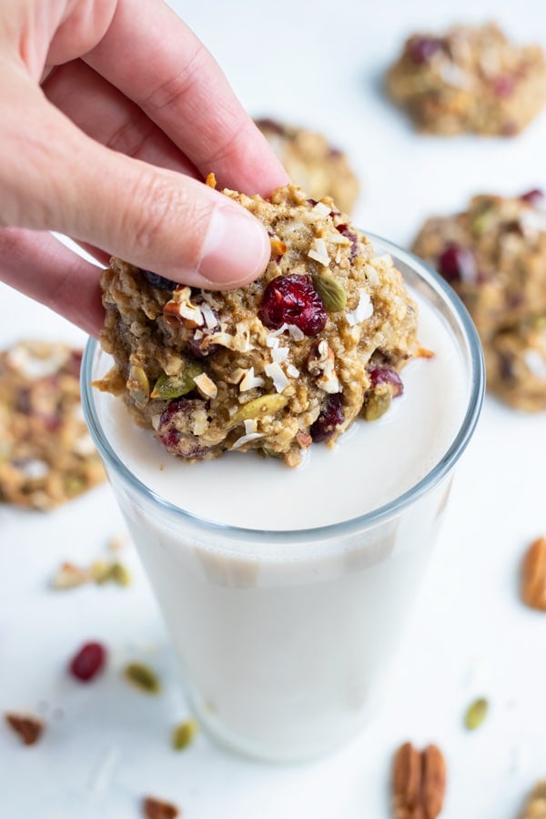 A healthy breakfast cookie is dumped in a glass of milk.