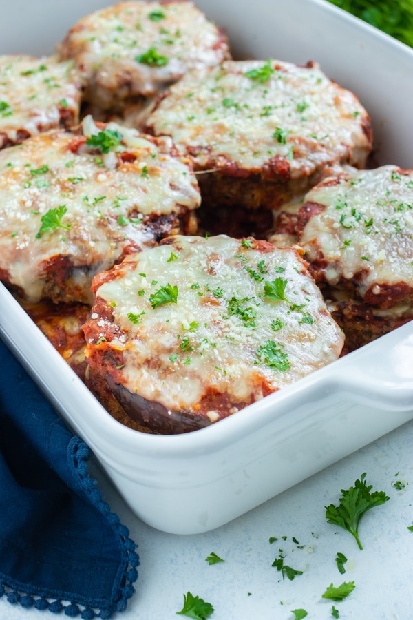 A baking dish is used to cook the servings of eggplant parmesan.