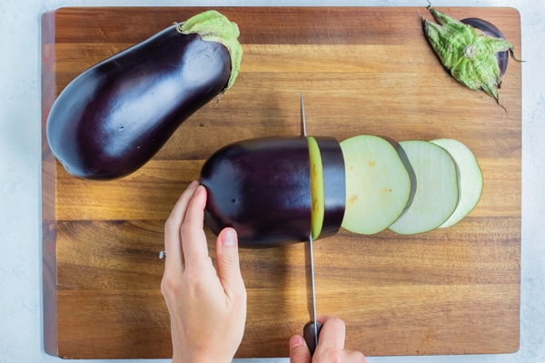An eggplant is sliced on the cutting board.