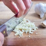 Carefully holding the knife, the garlic is minced.
