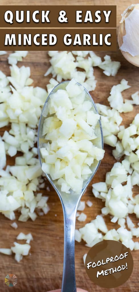 Minced garlic is set in a spoon on a cutting board.