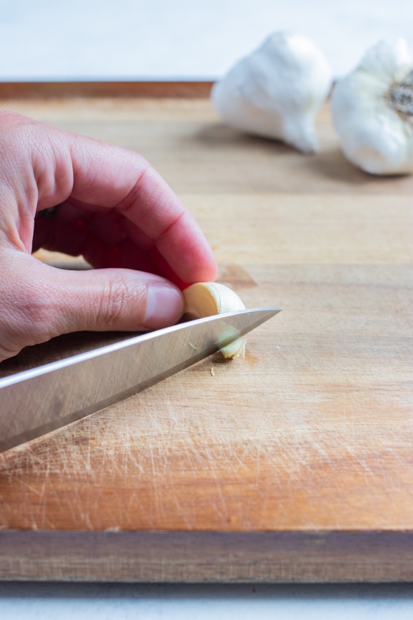 A knife is used to remove the tips of the garlic clove.