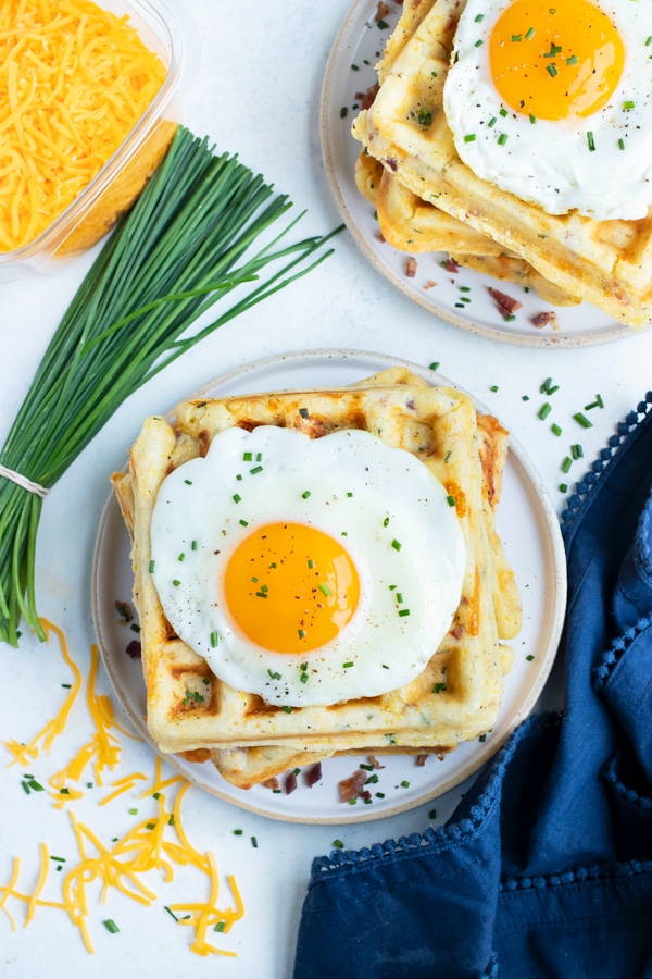 A fried egg is placed on top of the savory waffles.