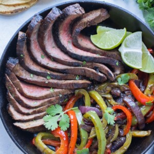 Vegetables and fajita steak are served with fresh limes.