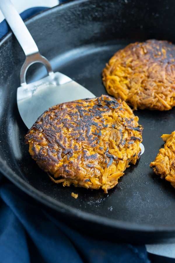 A spatula is used to flip the sweet potato hash browns.