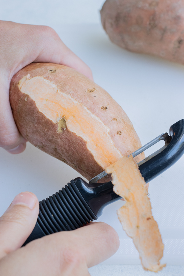 A vegetable peeler is used to peel the sweet potatoes.