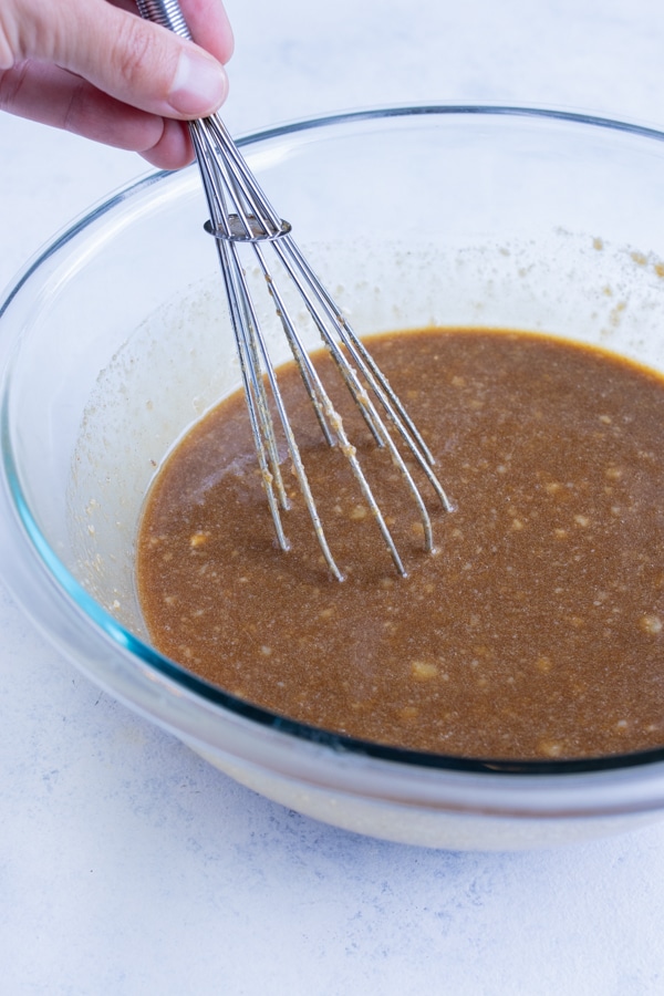 Sauce ingredients are combined in a glass bowl with a whisk.