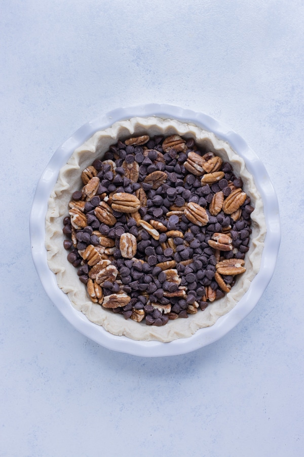 Pecans and chocolate are laid in a layer in the pie crust.