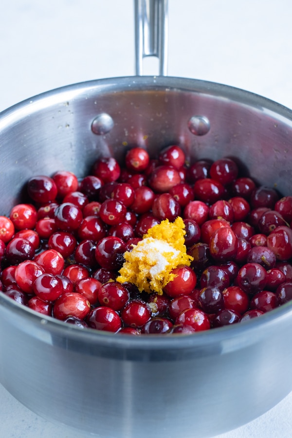 Whole cranberries, orange zest, and salt are added to the pot.