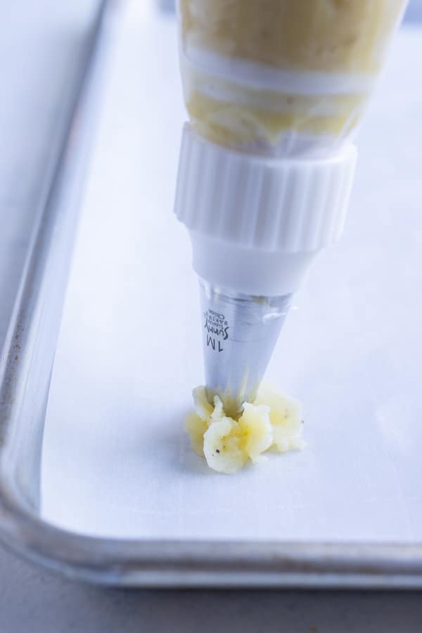 Potato mixture is piped from a pastry bag.