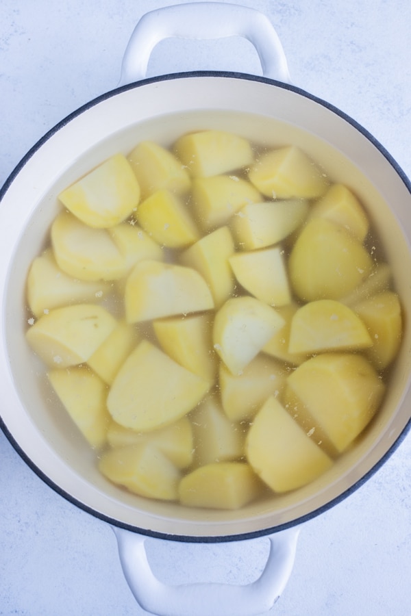 Diced potatoes are boiled on the stove in a pot.