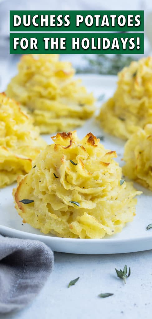 Golden and fluffy duchess potatoes are garnished with fresh herbs.