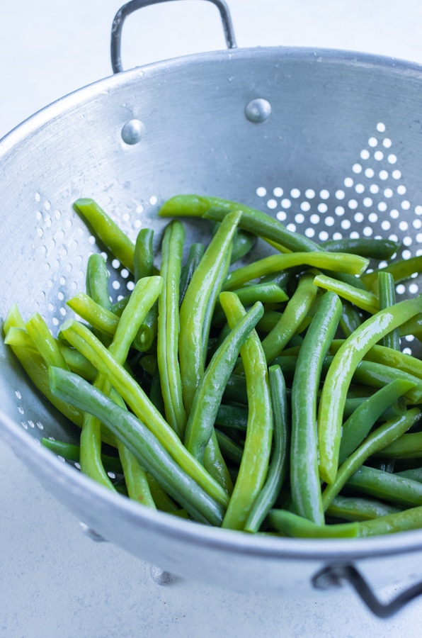 Green beans are drained in a colander after shocking.