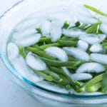Boiled green beans are placed in an ice water bath.