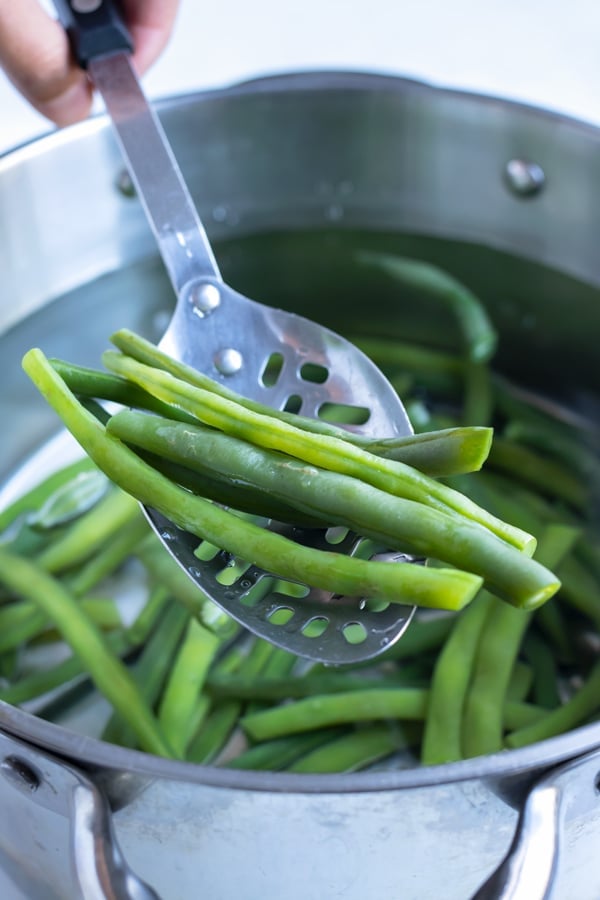 Beans are boiled in a pot of water.