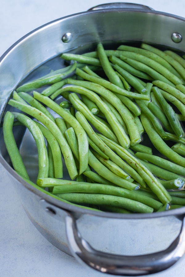 Green beans are placed into a pot of water.