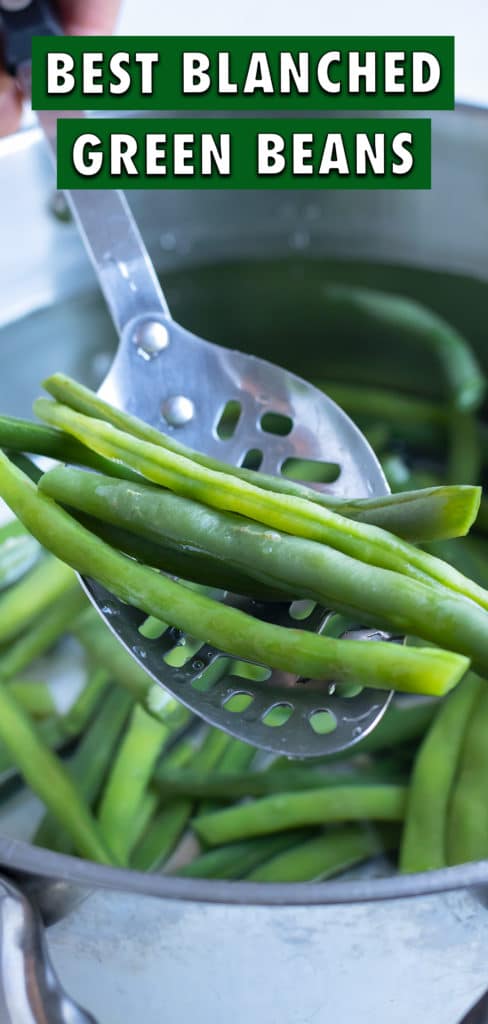 Green beans are removed from the pot by a spoon before blanching.