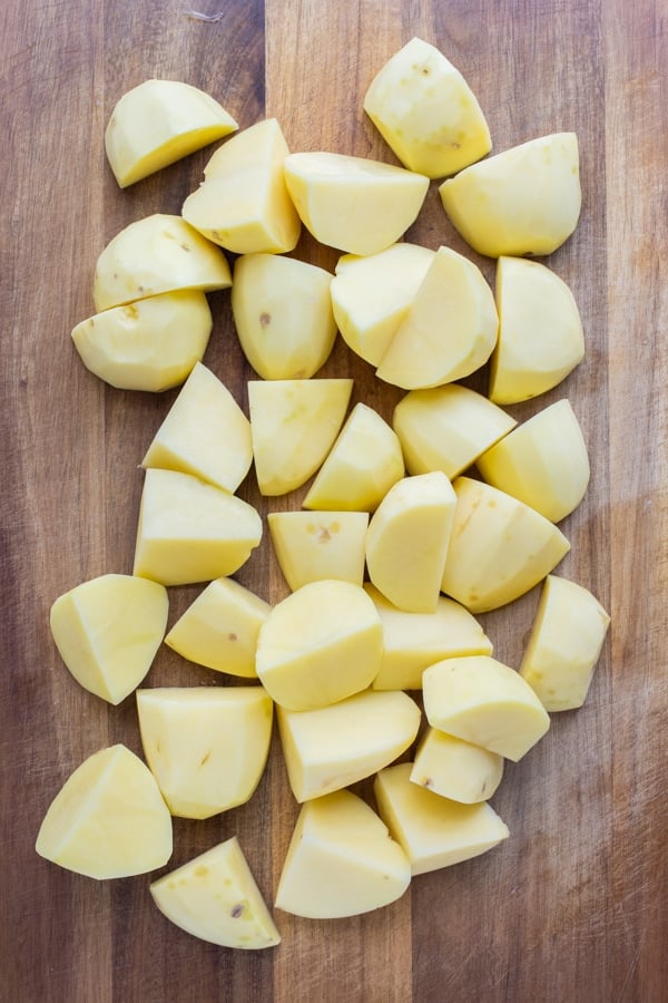 Diced and peeled potatoes are set on a cutting board.