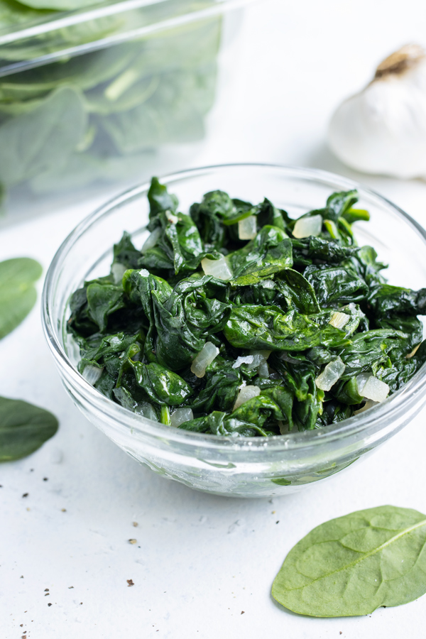 Spinach is sautéed and served in a glass bowl.