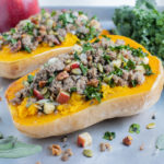 Sausage stuffed butternut squash is served on a tray for dinner.