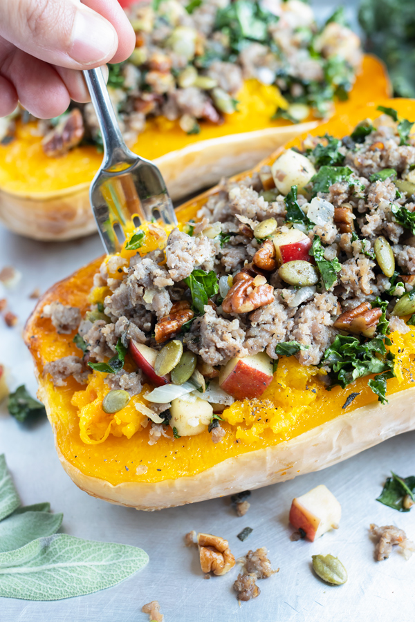 A fork is used to eat the roasted stuffed butternut squash.