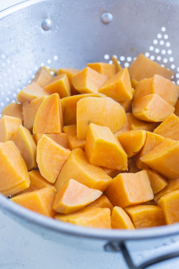 Cubed and tender boiled sweet potatoes are drained.