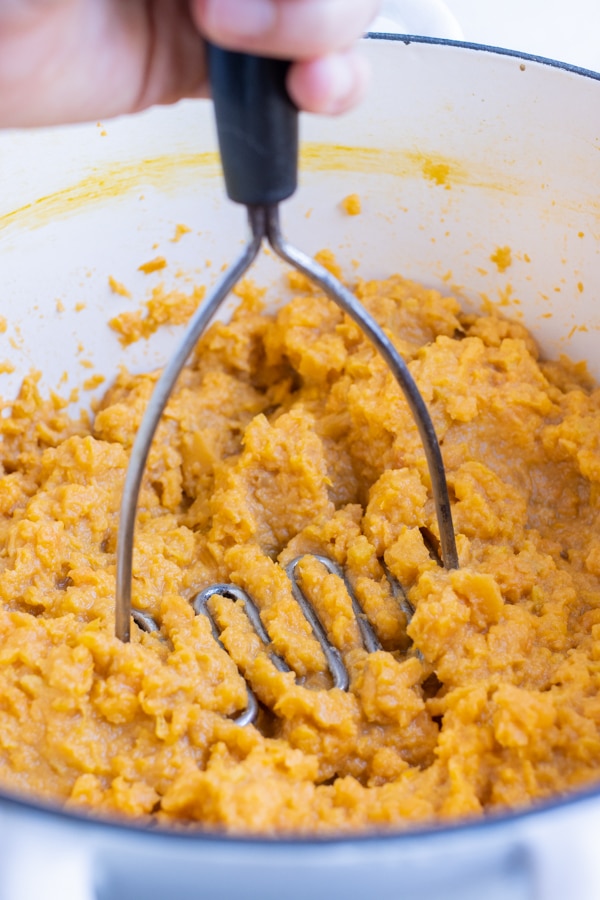 Sweet potatoes are mashed with a potato masher.
