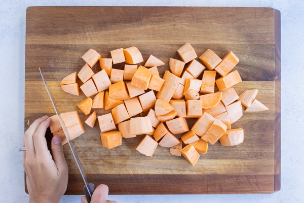 The sweet potatoes are cubed with a knife.