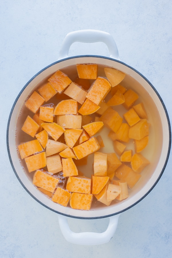 The cubed sweet potatoes are boiled in a pot.