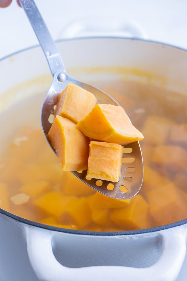 Tender sweet potatoes are removed from the water.