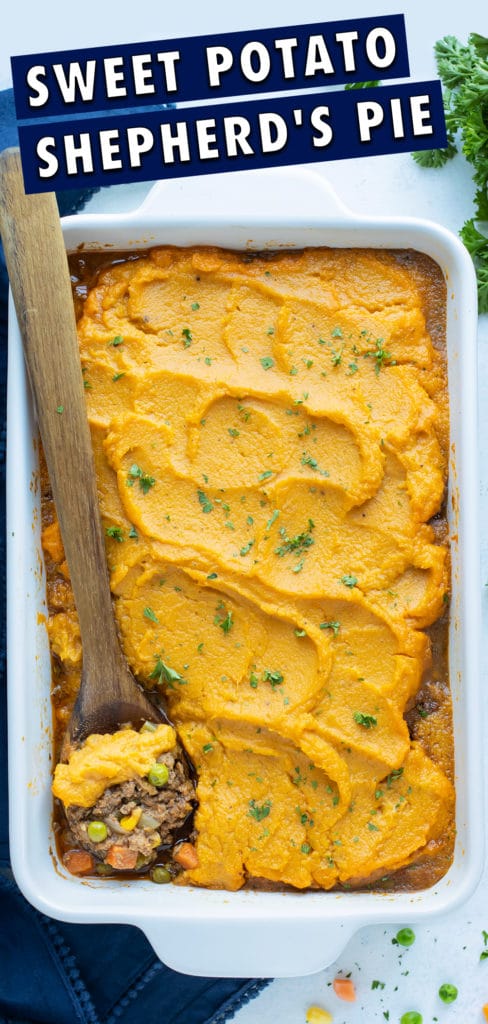 A wooden spoon is used to dish a serving of sweet potato shepherd's pie.