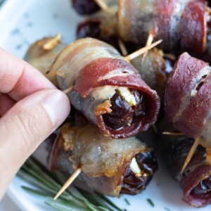 A hand is shown picking up a bacon wrapped date.