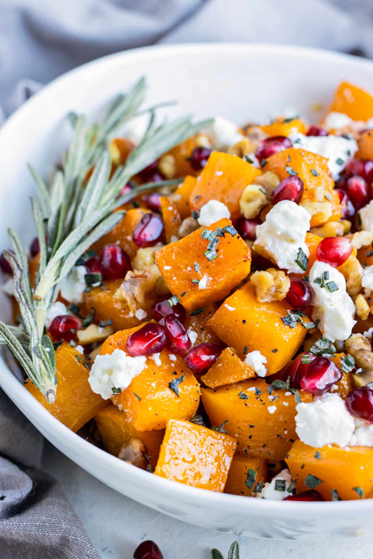 Roasted butternut squash and goat cheese are combined in the bowl with nuts and pomegranate seeds.