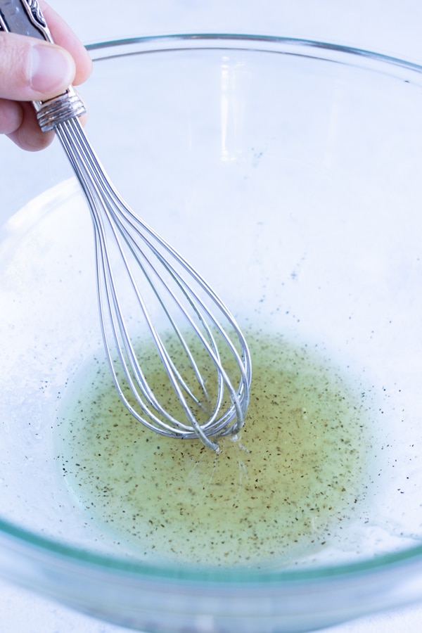 The oil and seasonings are whisked together in a bowl.