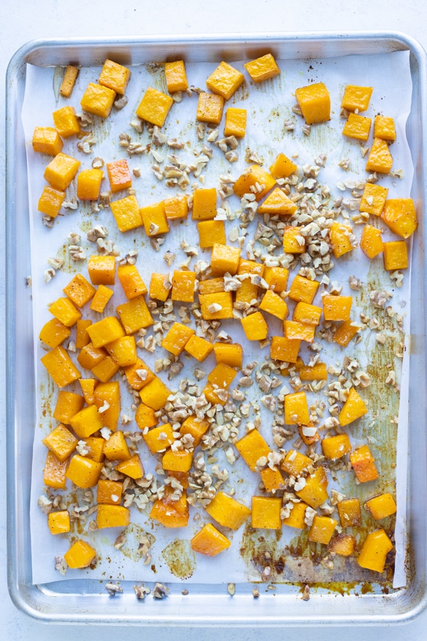 The chopped nuts are tossed on top of the butternut squash.