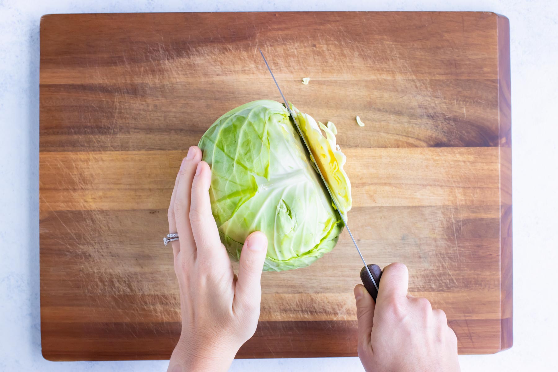 The end of the cabbage head is removed with a knife.