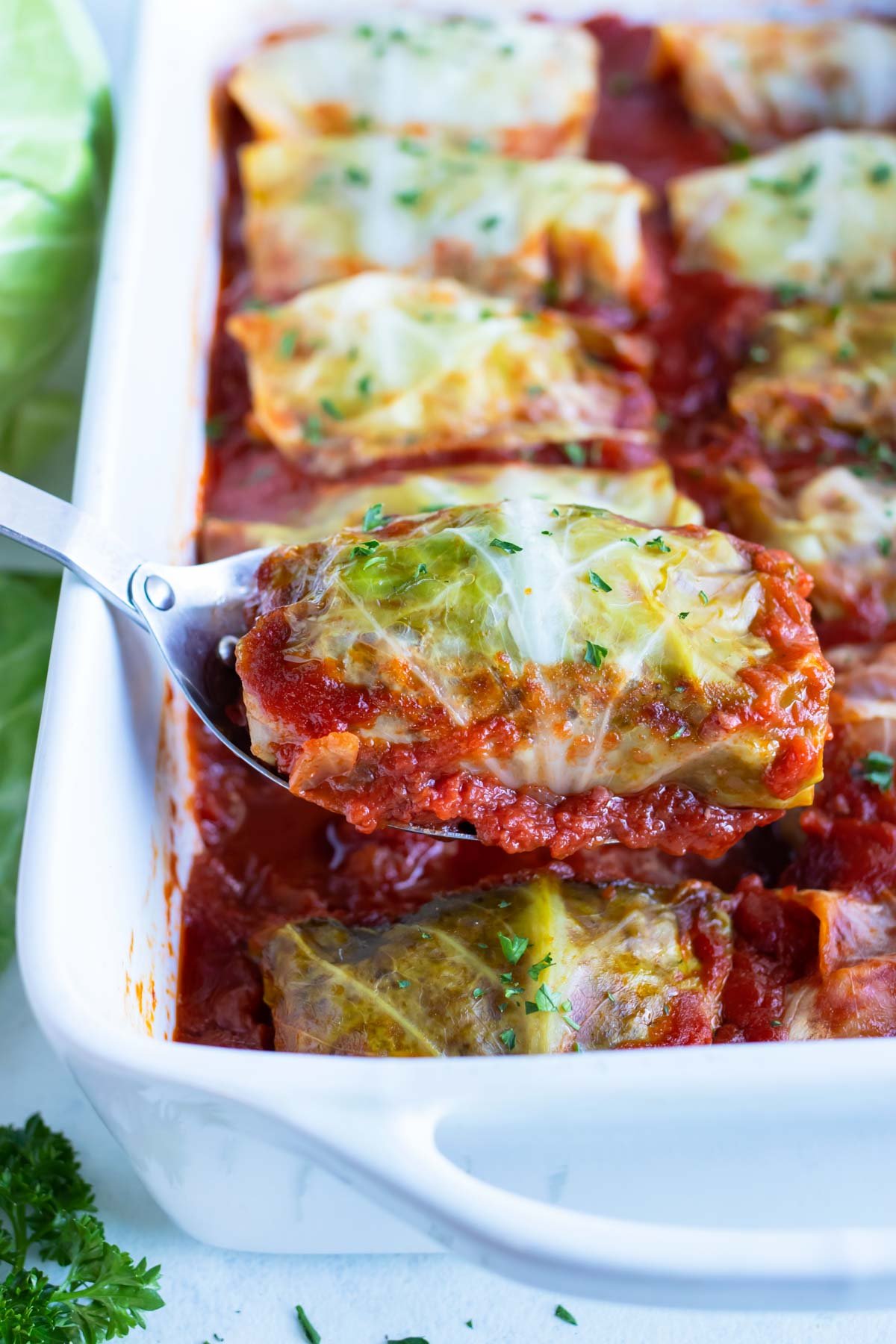 One cabbage roll is lifted out by a metal spoon.