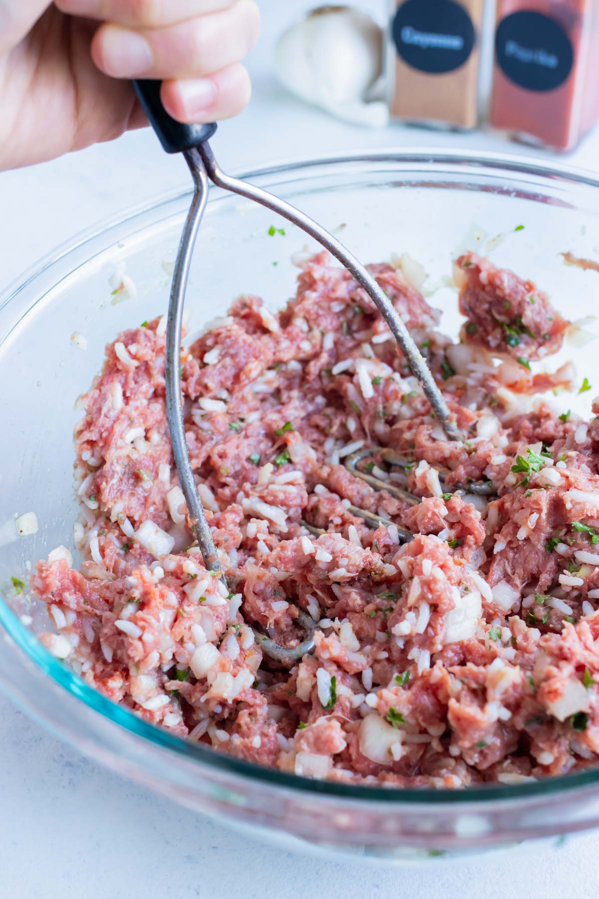 Ground meat, onion, spices, and egg are combined in a bowl.