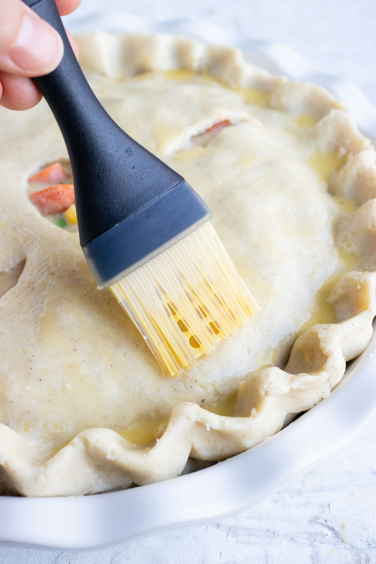 Melted butter is brushed on top of the pot pie crust.