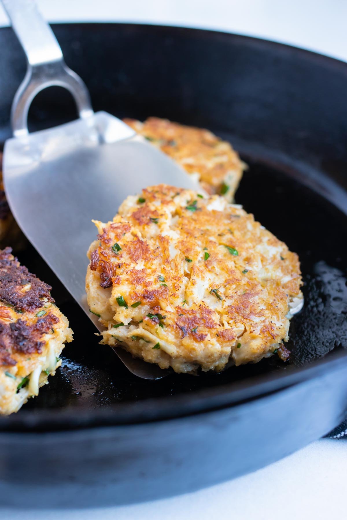 Maryland crab cakes are cooked in a skillet on the stove.