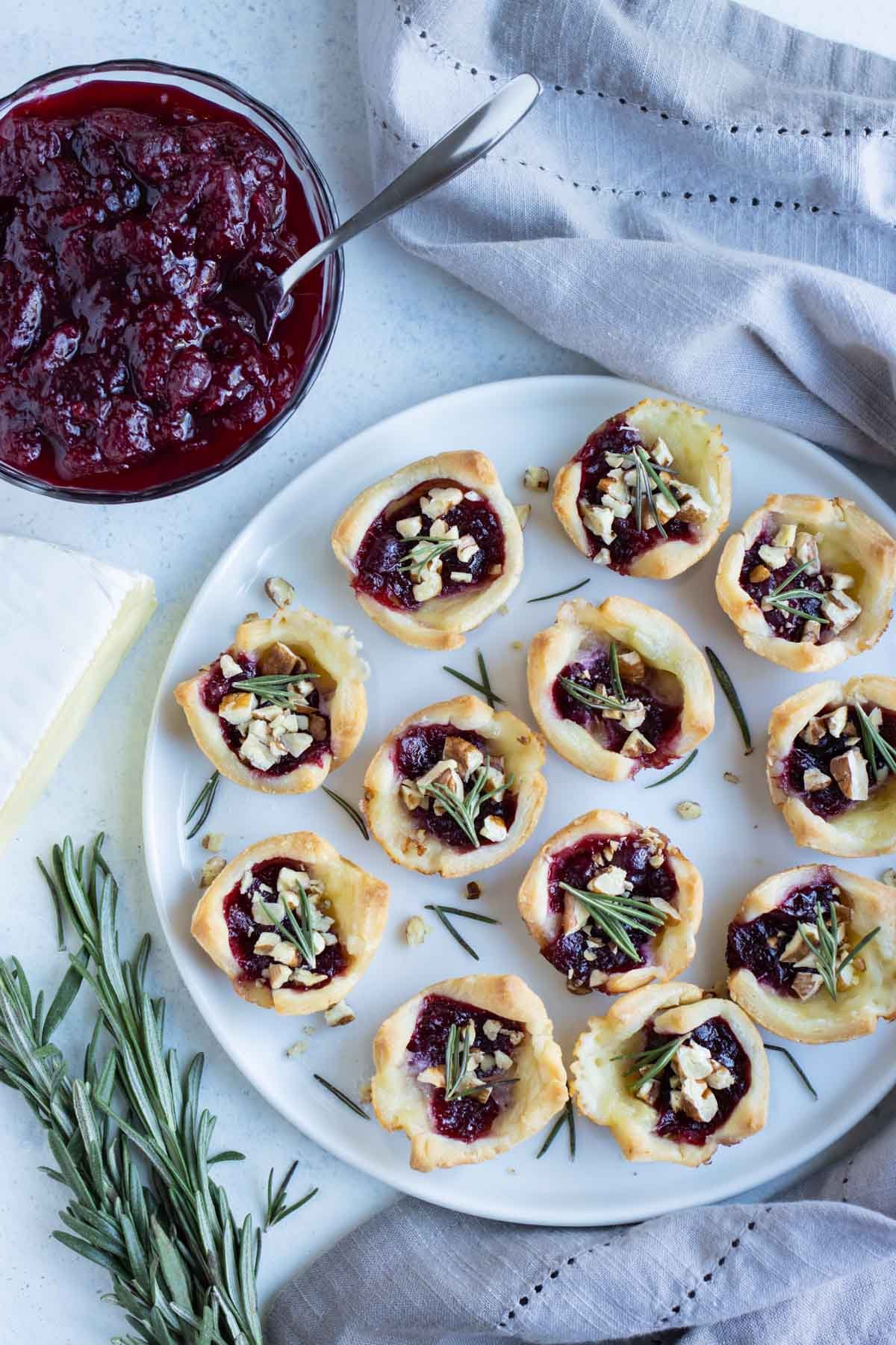 A full plate of cranberry brie bites is shown on the counter.