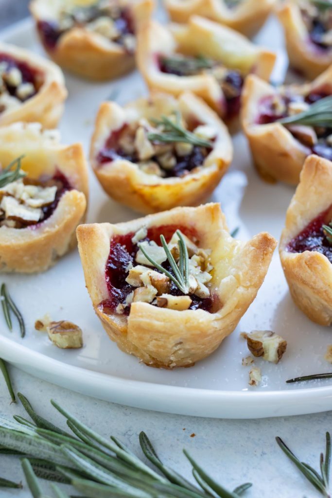 Golden puff pastry filled with cranberry and brie are plated for an appetizer.