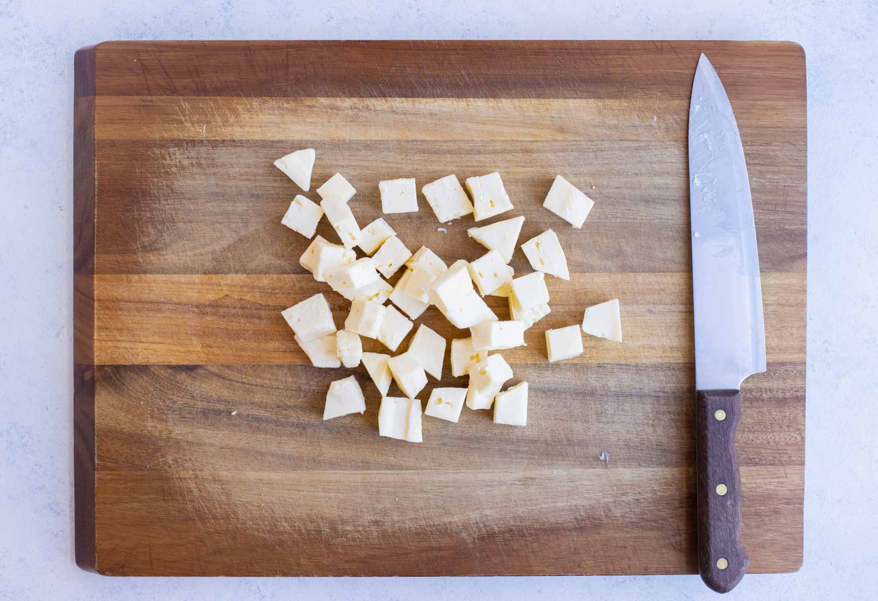 Pieces of brie are set on the cutting board before baking.