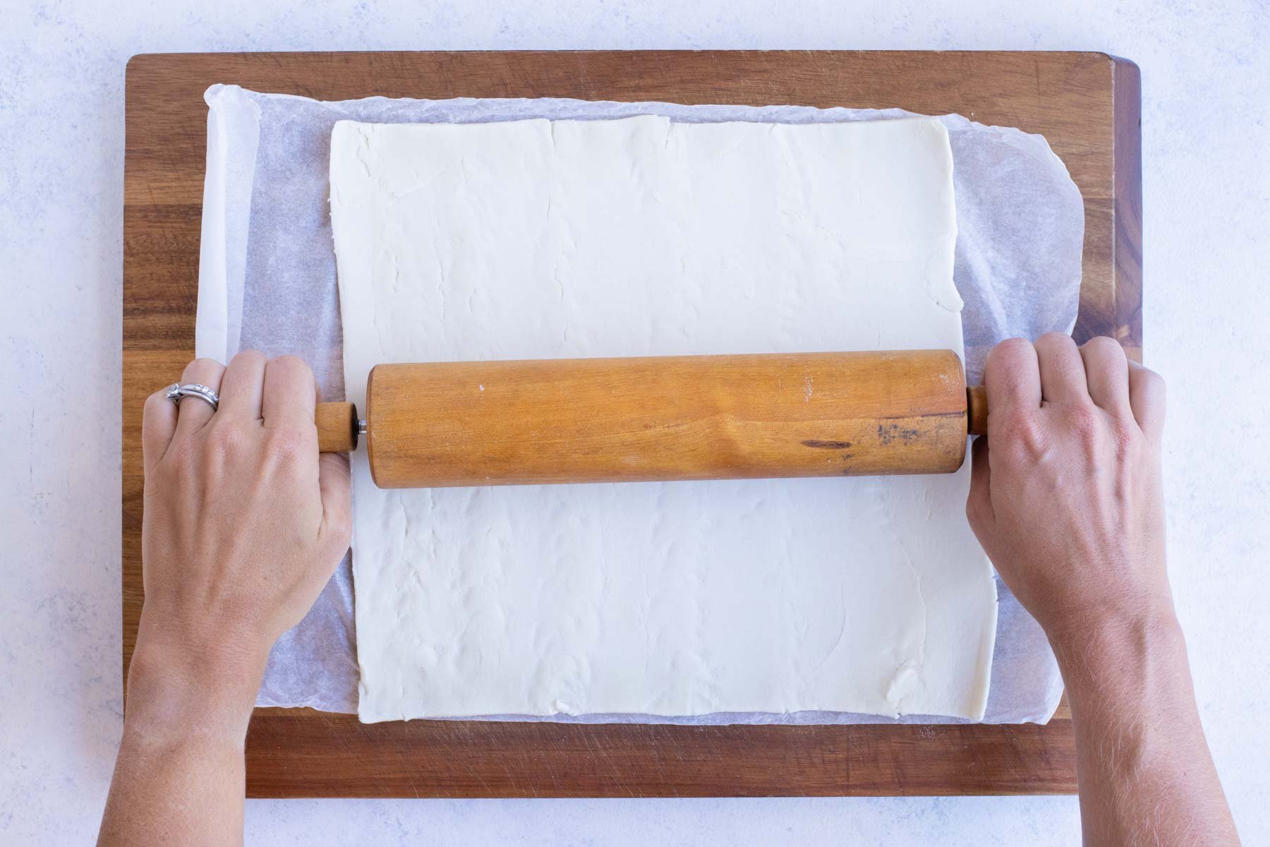 Puff pastry is rolled out with a rolling pin.