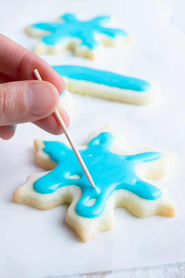 A toothpick spreading icing on a cookie.