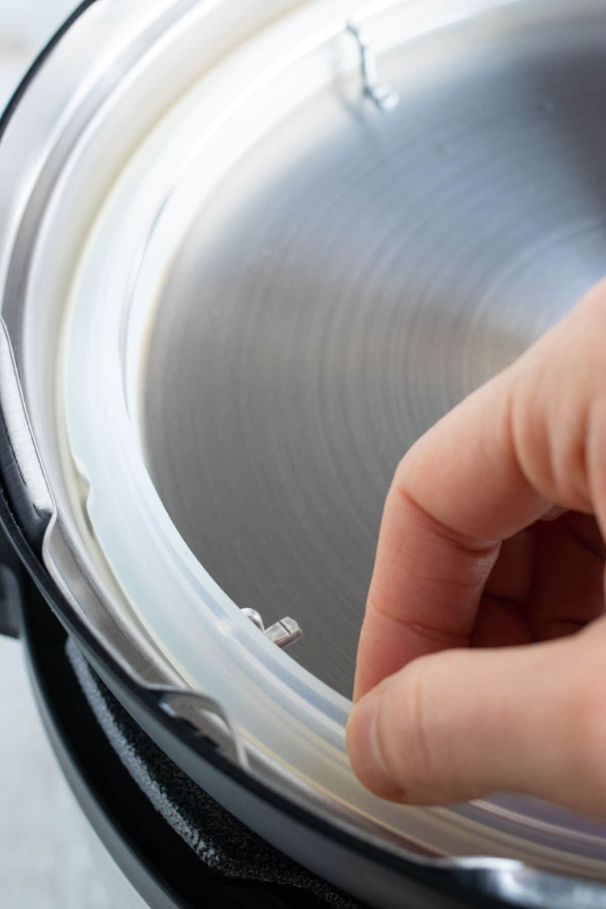 A hand removing and placing the silicone ring around the lid of an Instant Pot.